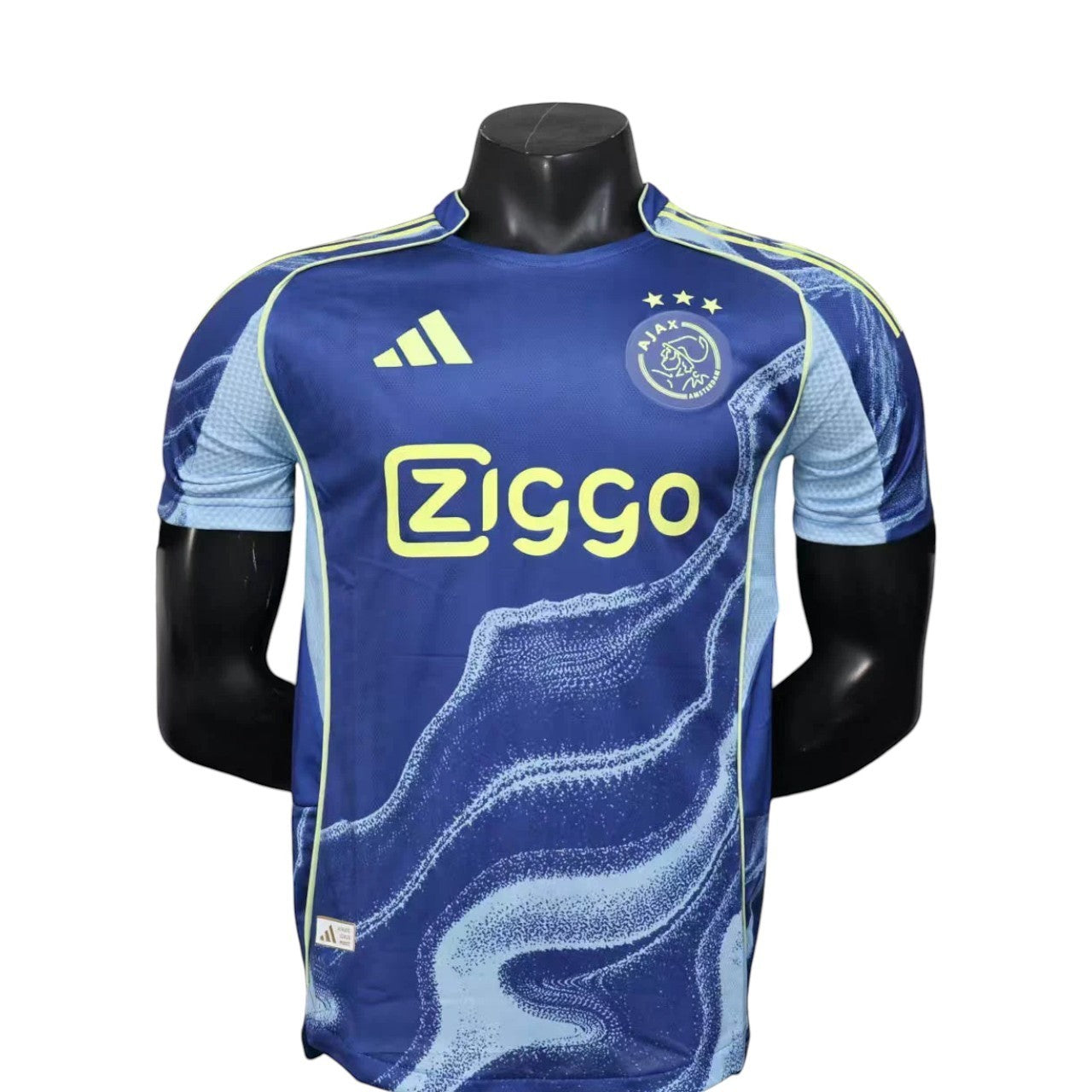 GOATkitz Ajax 2025-26 player version away jersey in blue with light blue wave pattern and yellow accents. Customizable.