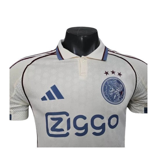 GOATkitz Ajax 2025-26 player version third jersey in cream with blue accents and club crest. Short sleeves, polo collar.