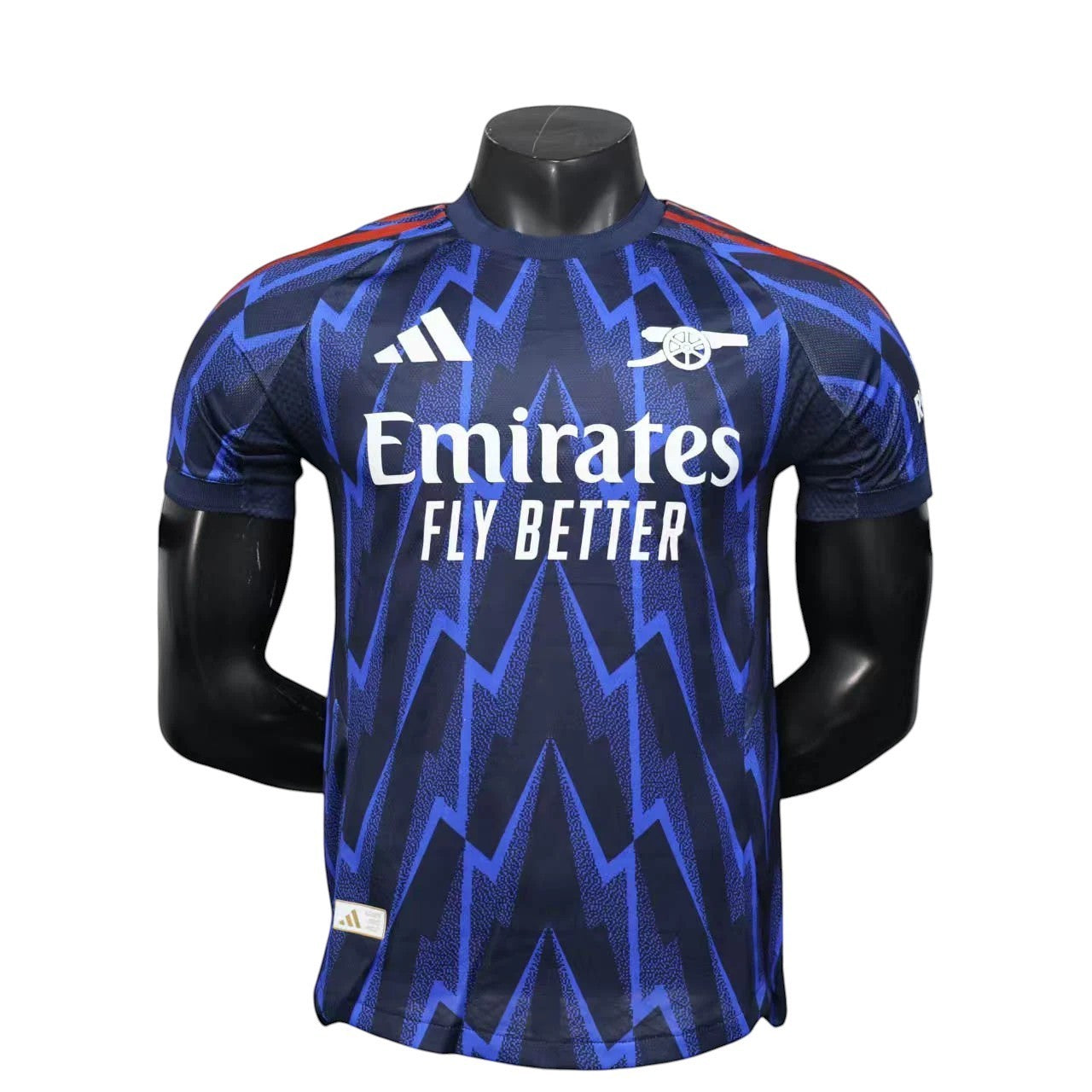 GOATkitz Arsenal 2025-26 adult player version away jersey in navy blue with a zigzag pattern and white Emirates Fly Better logo.