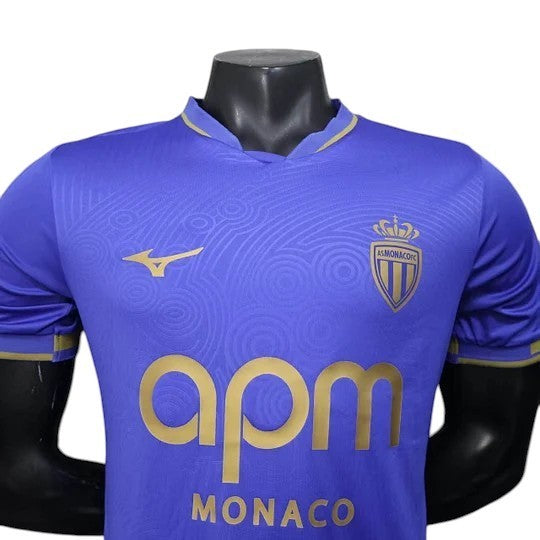 GOATkitz AS Monaco 2025-26 player version away jersey in royal blue with gold accents and crest. Features subtle circular pattern.