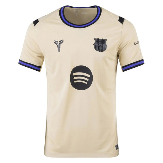 GOATkitz Barcelona 2025-26 away jersey in beige with black and blue trim. Features Kobe Bryant logo, FC Barcelona crest, and Spotify logo.