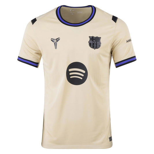 GOATkitz Barcelona 2025-26 kids away jersey in beige with black and blue trim. Features Kobe Bryant logo and Spotify sponsor.