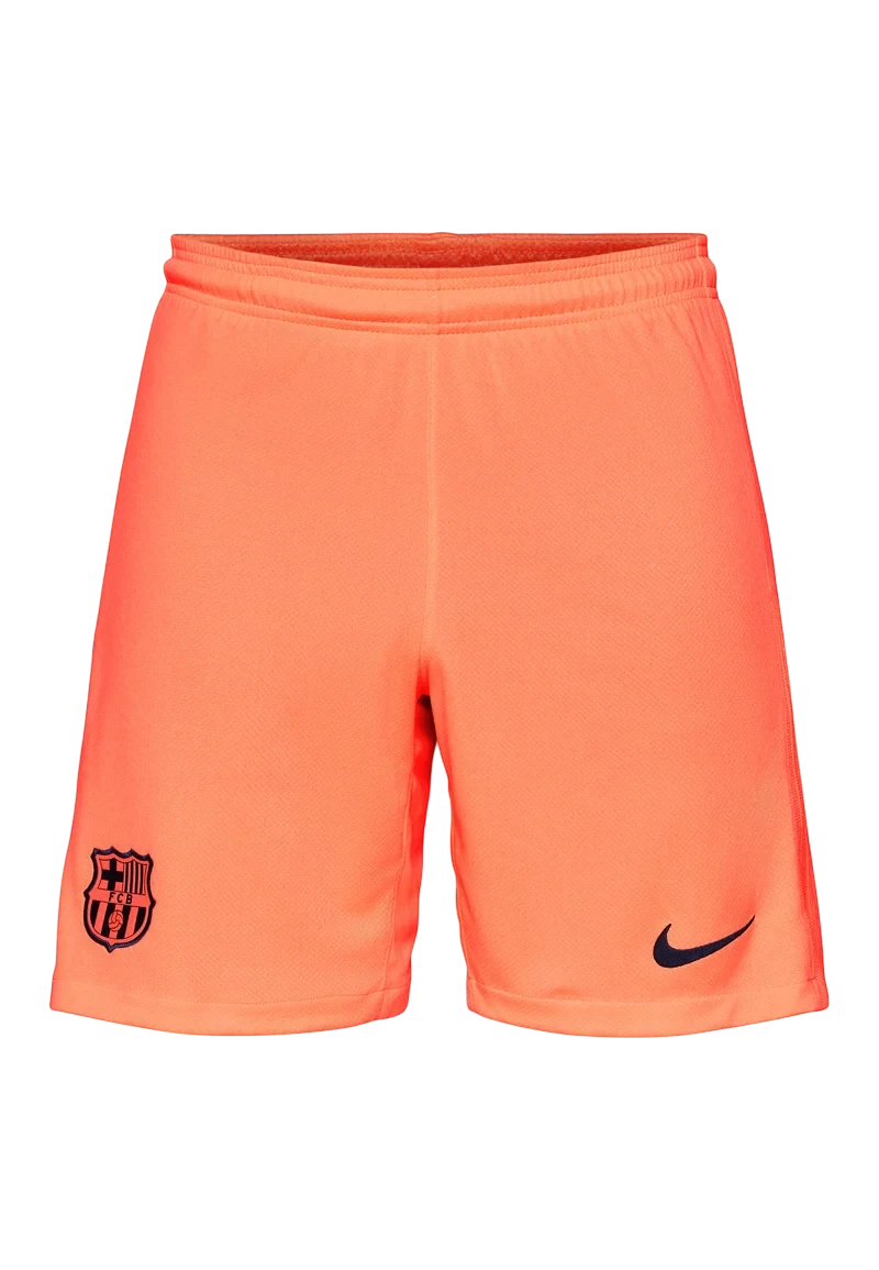 GOATkitz Barcelona 2025-26 kids third shorts in bright orange with navy FCB crest and Nike swoosh logo.