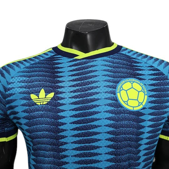 GOATkitz Colombia 2026 player version away jersey in blue with yellow accents. Features a repeating wave pattern, Adidas logo, and Colombia crest.