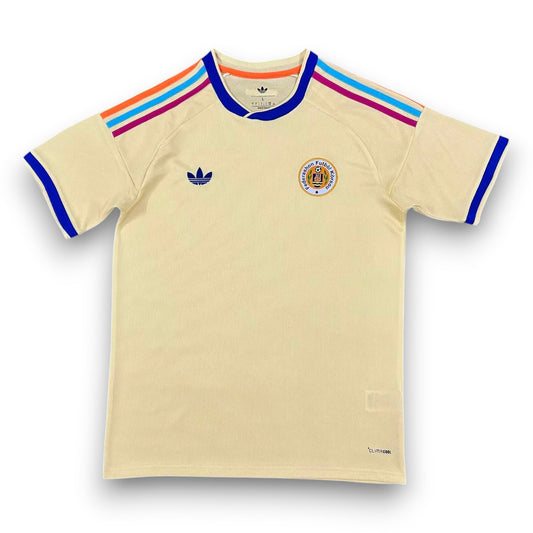 GOATkitz Curaçao 2026 adult away jersey in cream with blue trim and colourful Adidas stripes on the shoulders.