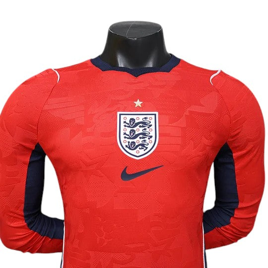 GOATkitz England 2026 player version long sleeve away jersey in red with navy blue accents and the England crest.