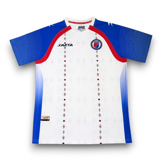 GOATkitz Haiti 2026 adult away jersey, white with blue sleeves and red accents. Features subtle snowflake-like pattern and customizable options.