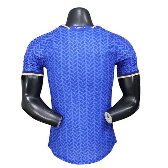 GOATkitz Italy 2026 player version home jersey in blue with a subtle leaf pattern and beige trim. Features 'Azzurra' on the collar.