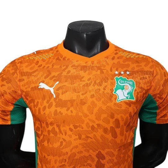 GOATkitz Ivory Coast 2026 player version home jersey in orange with green accents and a subtle abstract pattern. Features Puma logo and national crest.