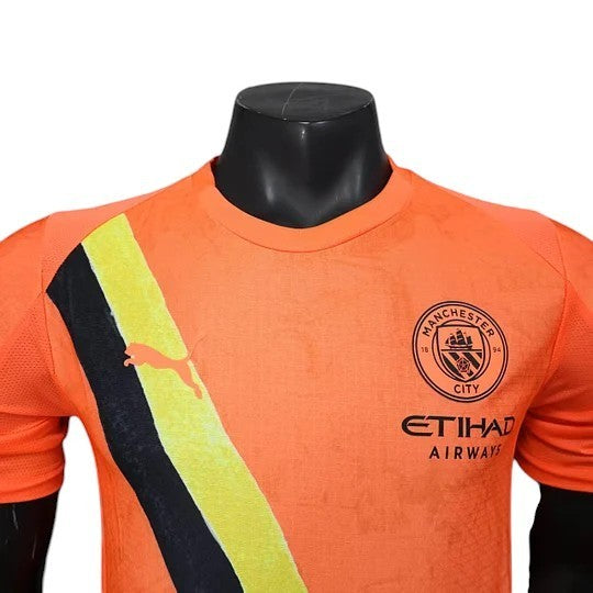 GOATkitz Manchester City x KidSuper 2025-26 player version orange jersey with black and yellow stripe detail. Customizable.