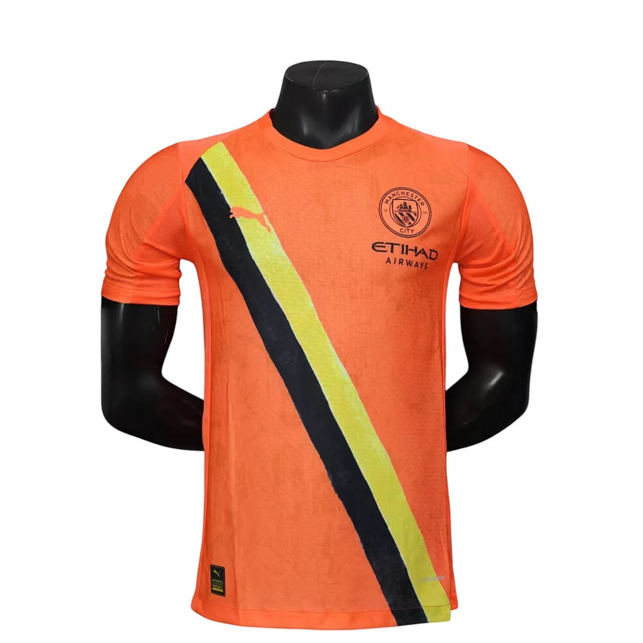 GOATkitz Manchester City x KidSuper 2025-26 player version orange jersey with black and yellow stripe detail.