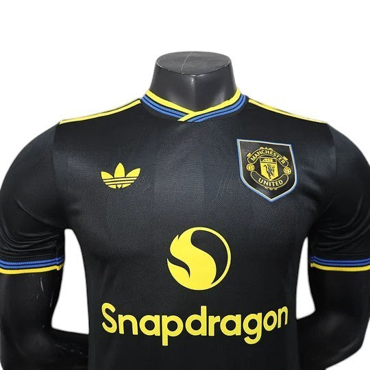 GOATkitz Manchester United 2025-26 black player version third jersey with yellow and blue trim. Features Adidas logo, club crest, and Snapdragon sponsor.