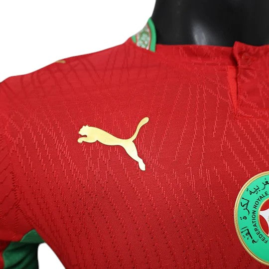 GOATkitz Morocco 2026 Player Version Home Jersey in red with gold Puma logo and Moroccan crest. Features a textured pattern.