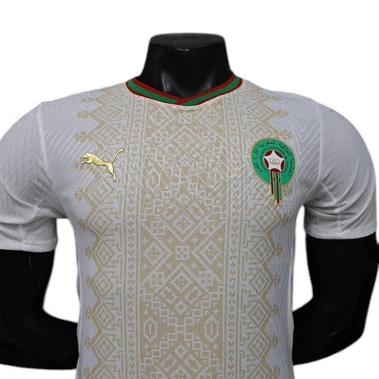 GOATkitz Morocco 2026 player version away jersey in white with gold Puma logo and intricate geometric pattern. Red and green collar.