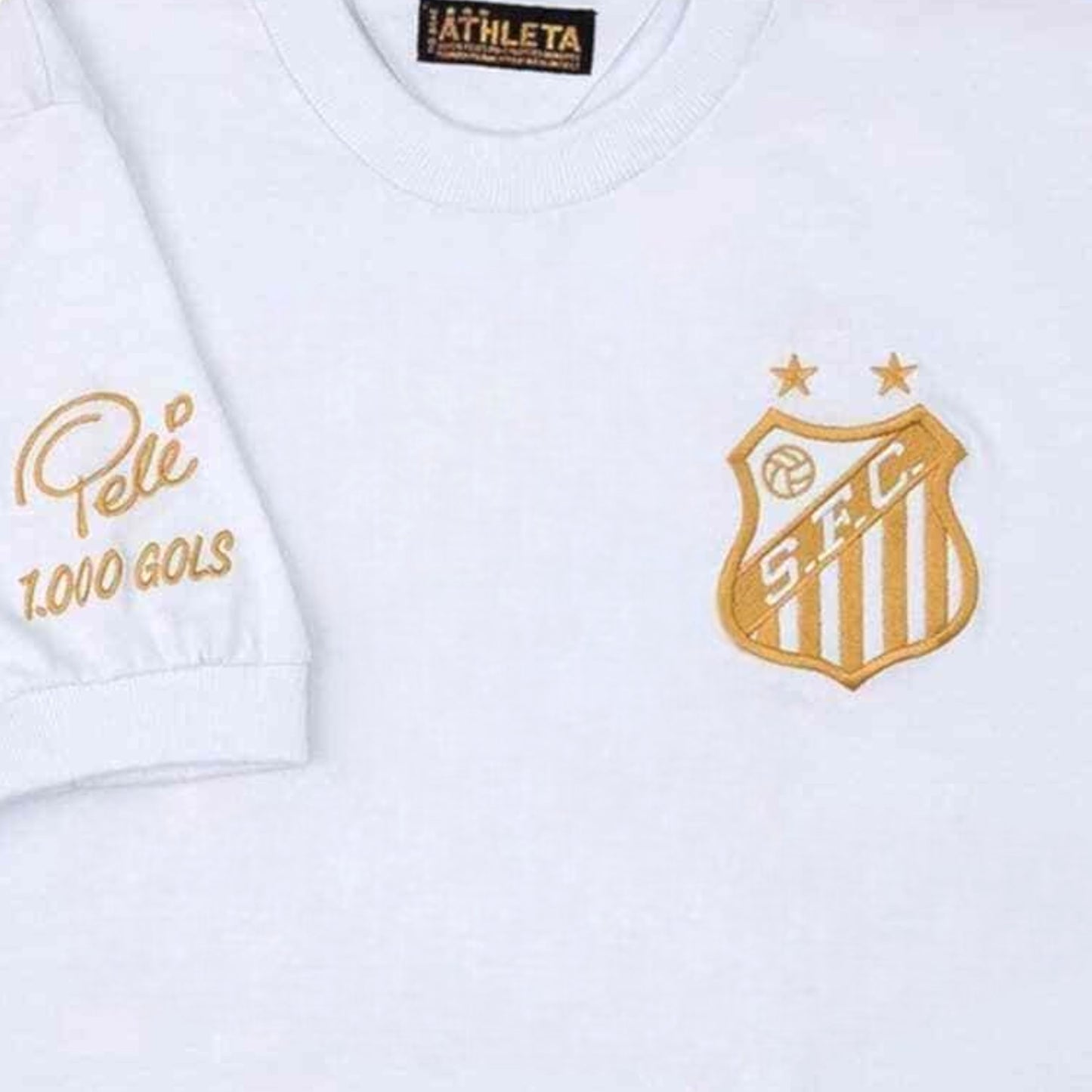 GOATkitz white commemorative football jersey with gold embroidered Santos crest and "Pelé 1.000 GOLS" detail on sleeve.