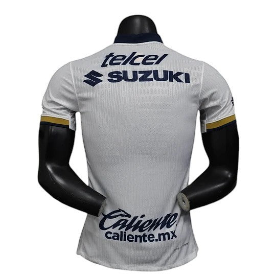 GOATkitz white Pumas UNAM 2025-26 player version soccer jersey with navy collar and gold trim on sleeves. Features Suzuki and Telcel logos.