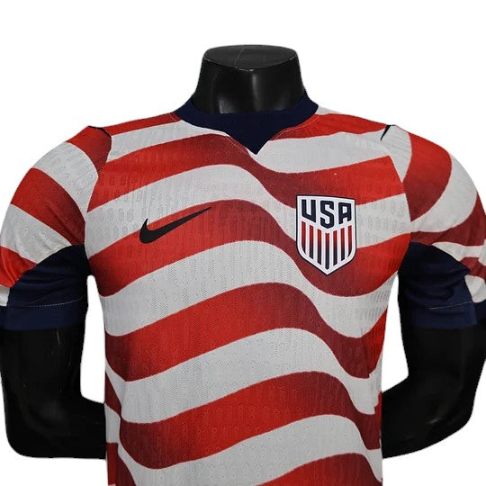 GOATkitz USA 2026 player version home jersey with red and white wavy stripes, navy collar, and USA crest.